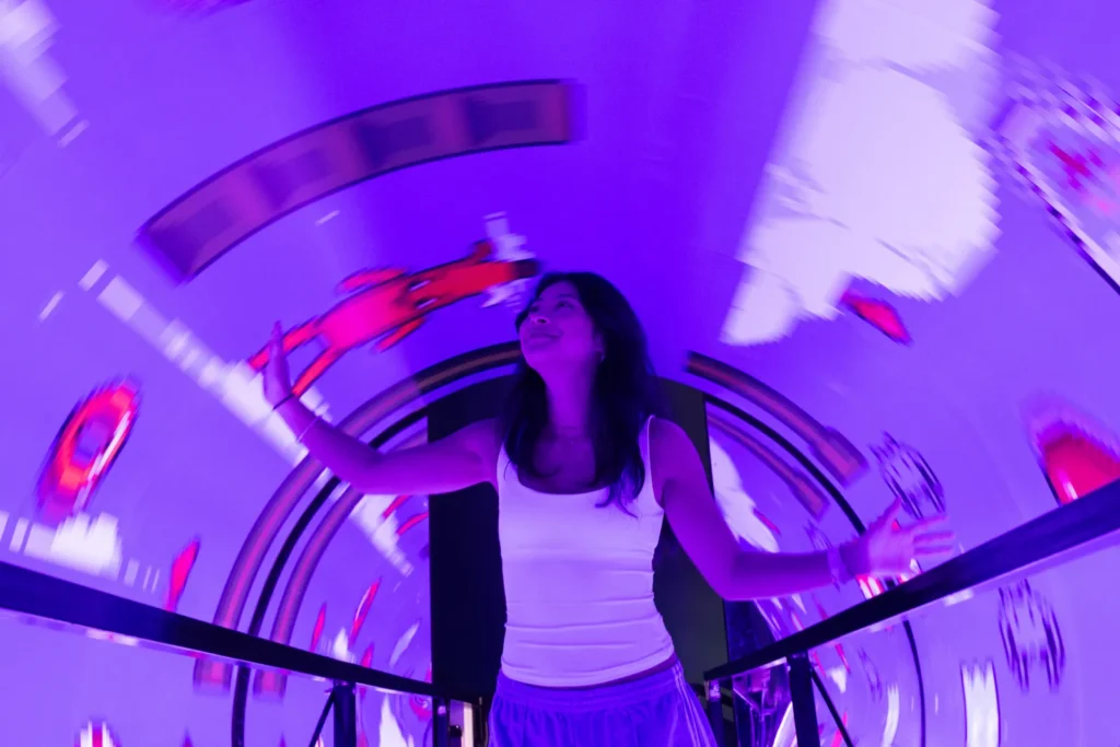 A visitor experiencing a vibrant purple rotating tunnel illusion at Mind Games Sydney, surrounded by swirling lights and distorted motion effects.