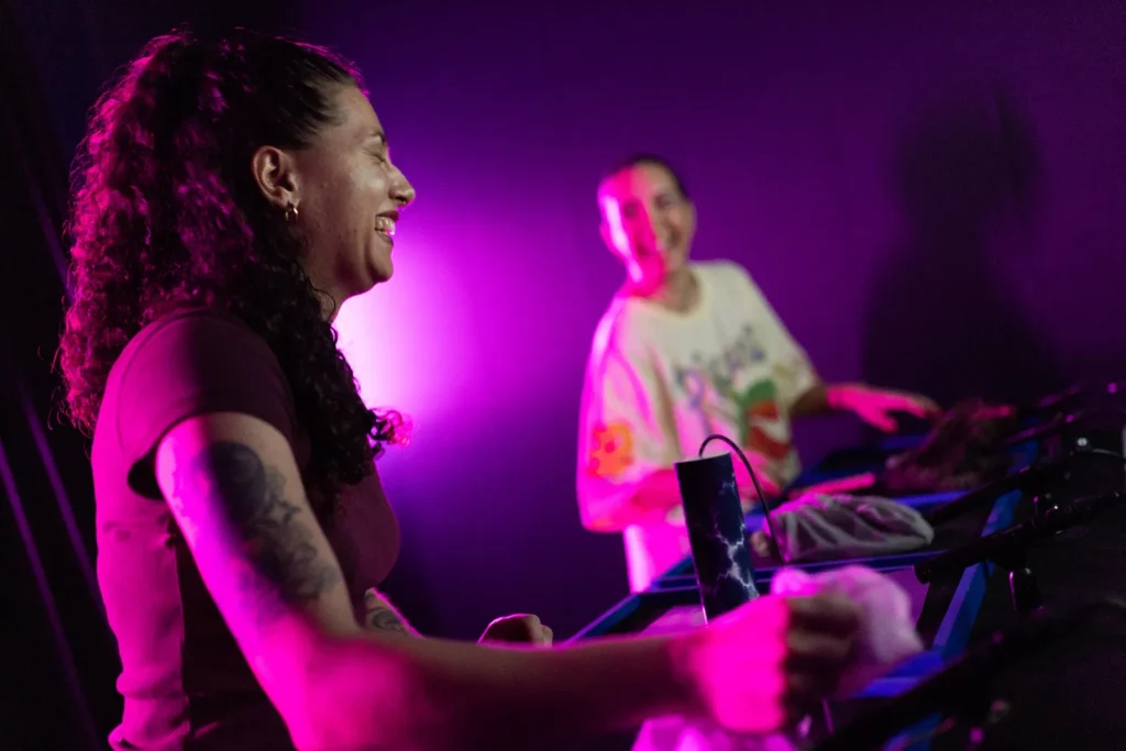Two visitors enjoying an interactive exhibit under vibrant pink and purple lighting at Mind Games Sydney.