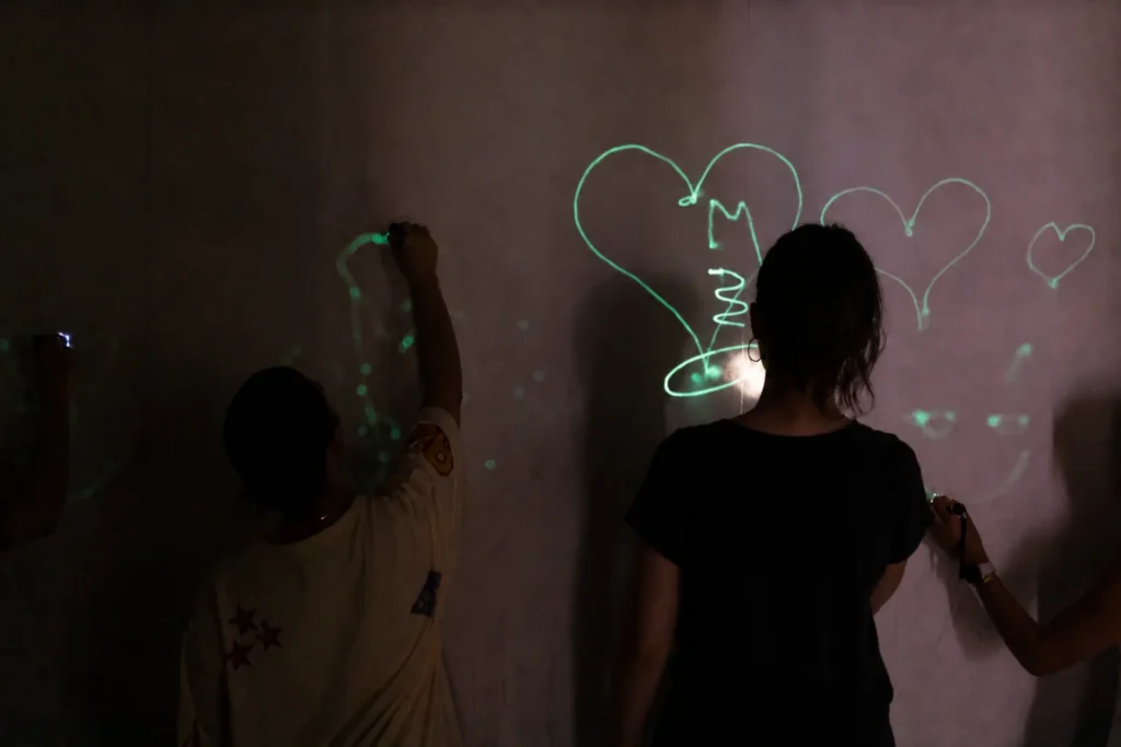 Visitors drawing glowing shapes and hearts on an interactive light wall at Mind Games Sydney.