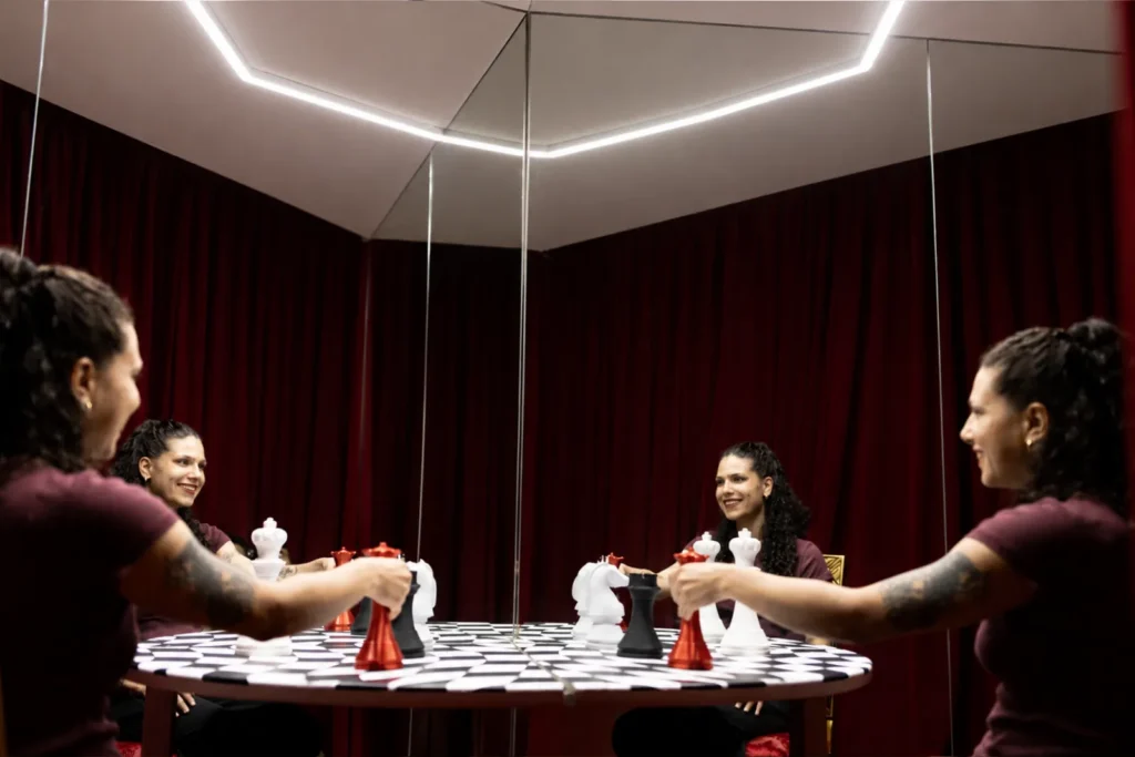 A visitor playing chess against multiple mirror reflections of herself in an illusion room at Mind Games Sydney.